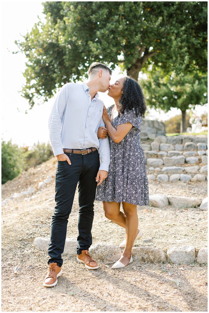 portrait of the couple sharing a kiss on a stone stairway