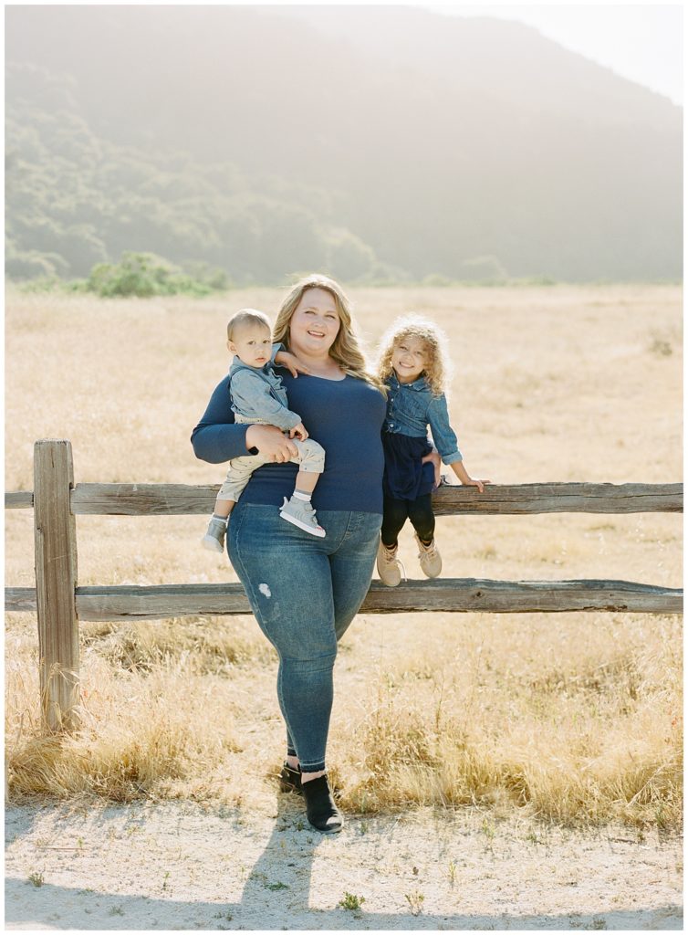 portrait of Mom with her son and daughter against a wooden fence with a field in the background by film photographer AGS Photo Art