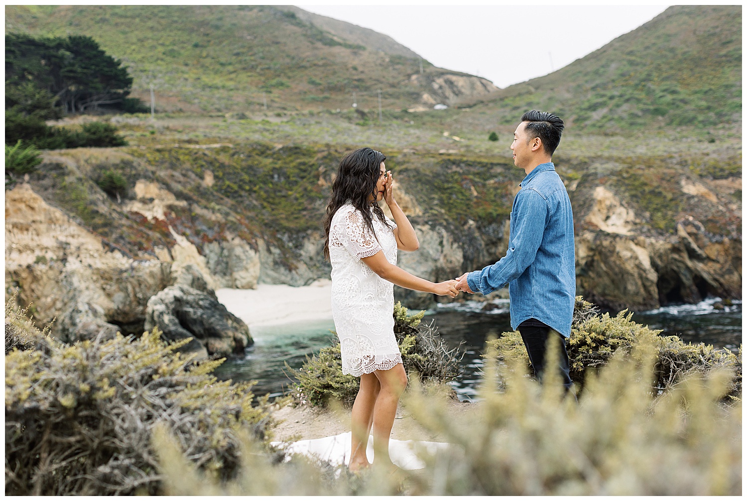 couple on the cliffs of Big Sur; the woman in a white dress tearing up over her Glen Oaks Big Sur surprise proposal