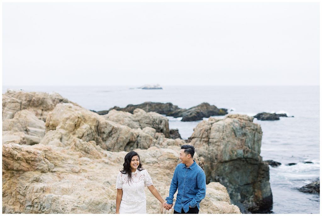couple hand in hand with the cliffs and waves behind them by film photographer AGS Photo Art