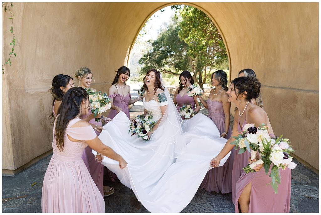 bride and her bridesmaids helping with her dress