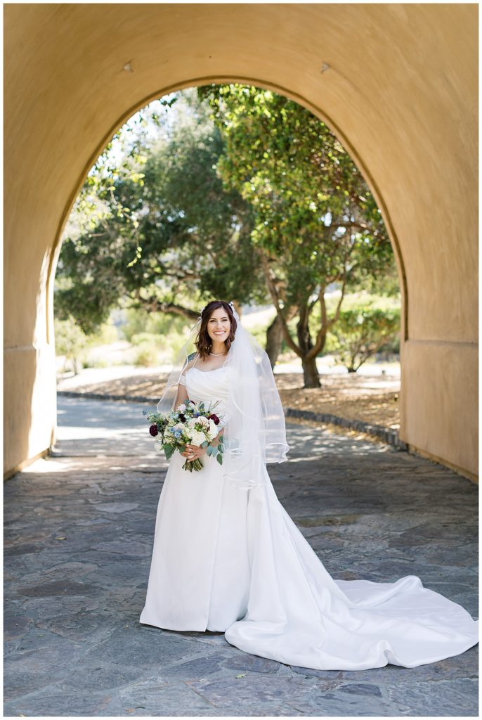 Monterey wedding at The Club At Pasadera portrait of the bride and her bouquet under an archway