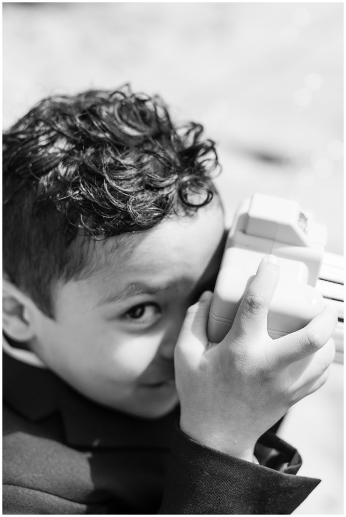 black and white portrait of bride and groom's son with a toy camera