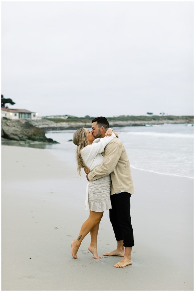 portrait of the couple sharing a kiss with the waves behind them