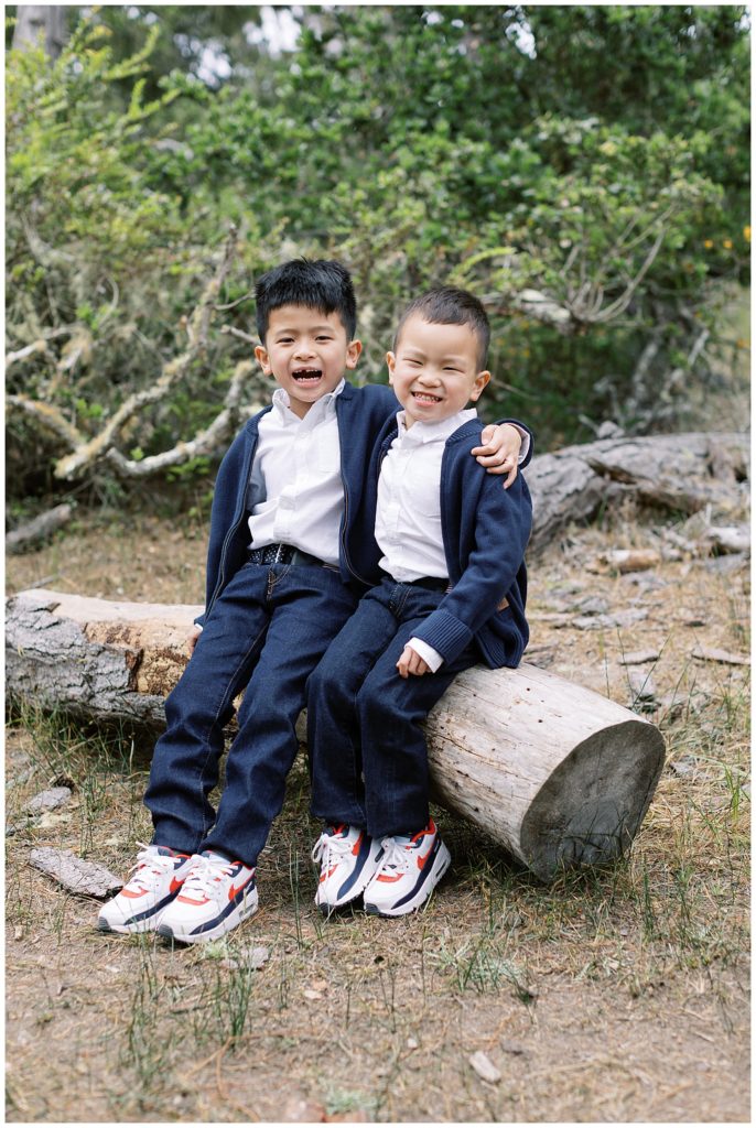 portrait of brothers sitting on a log and smiling at the camera by film photographer AGS Photo Art