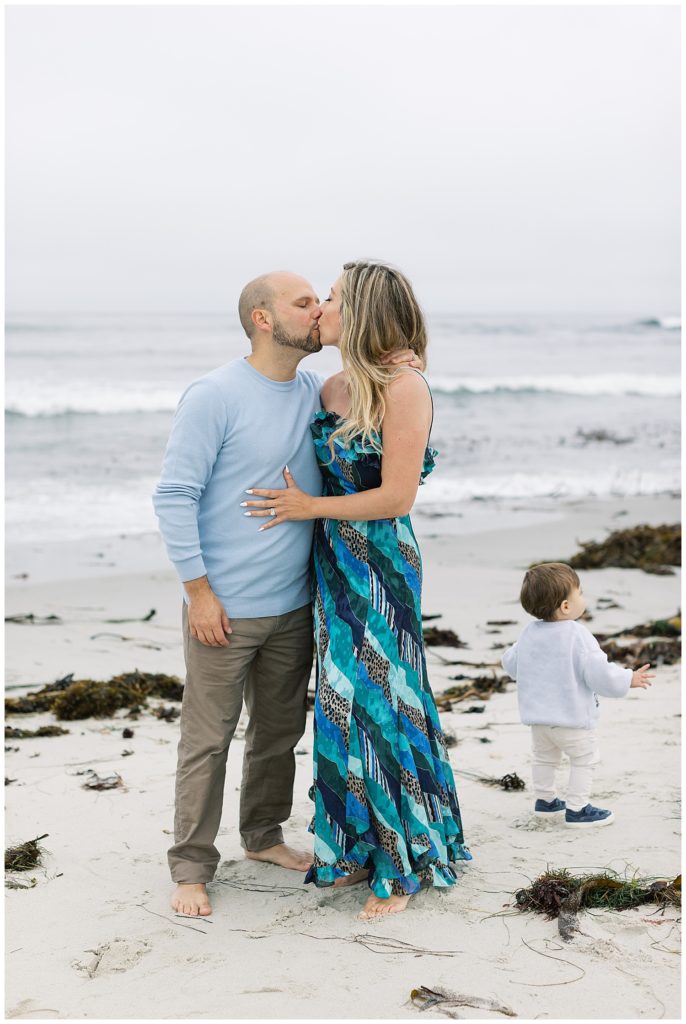 kissing couple portrait at Pebble Beach; toddler is facing away from Mom and Dad