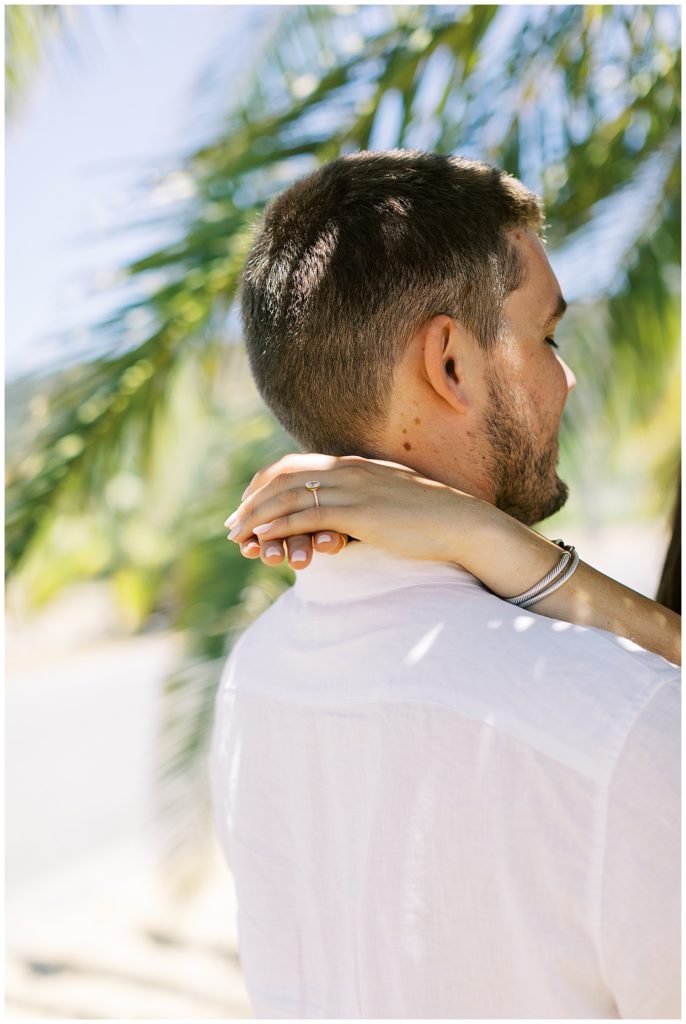 photo of a woman's hands behind her fiancé's neck