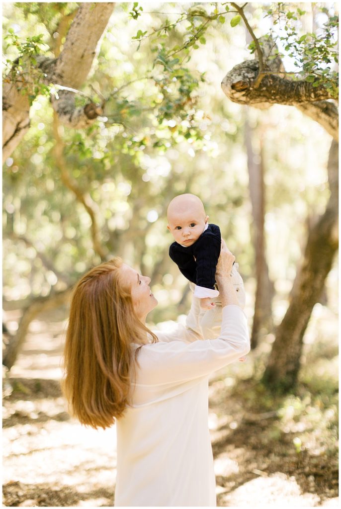 Mom holding her newborn up in the air in the Del Monte Forest