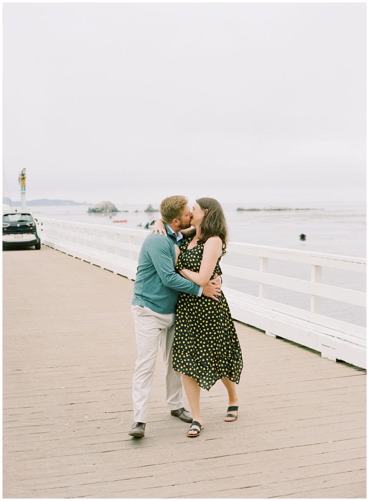 portrait of couple sharing a kiss on the pier at Pebble Beach