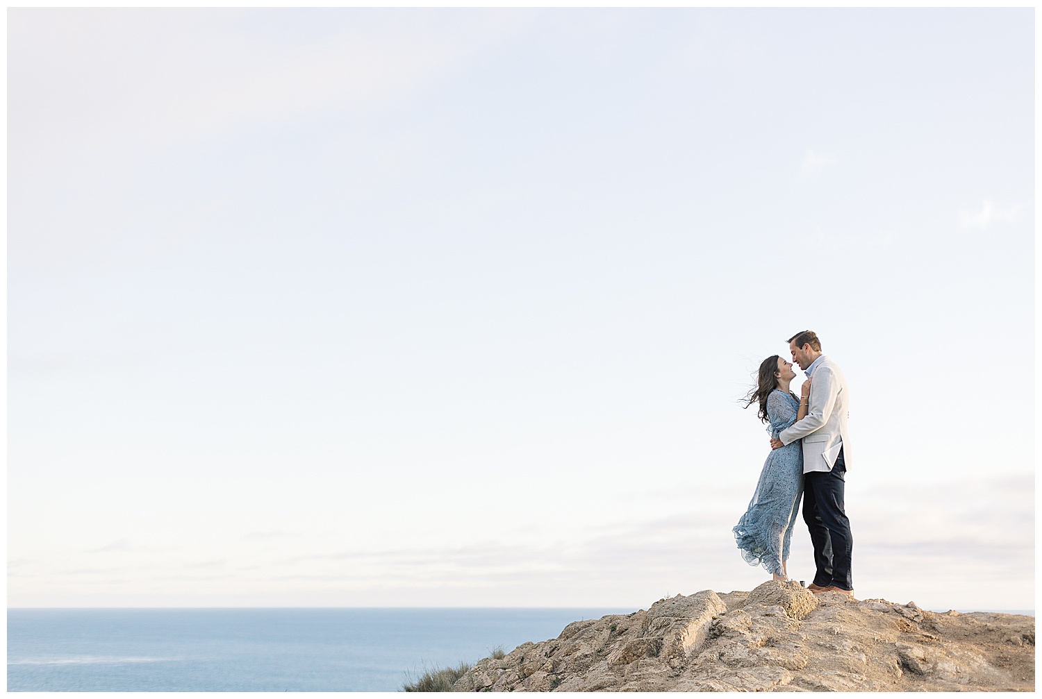 photo of couple embracing near the top of a cliff with the ocean behind them by film photographer AGS Photo Art