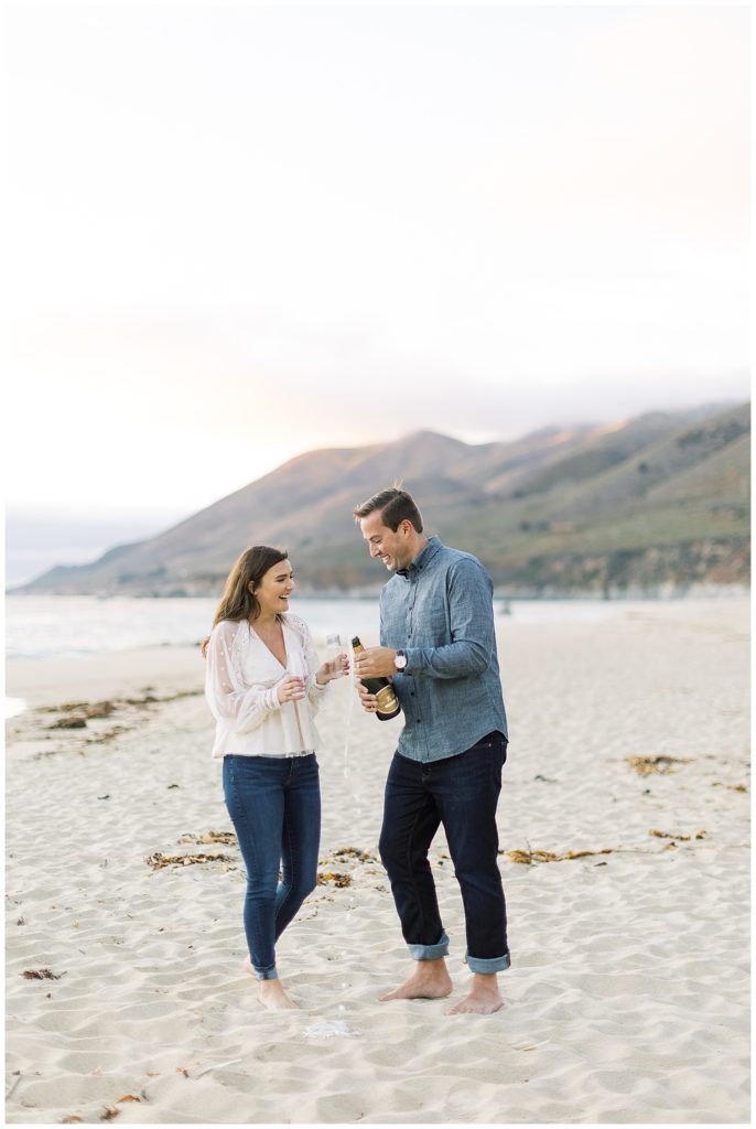 couple celebrating their Big Sur engagement at the beach with champagne by film photographer AGS Photo Art