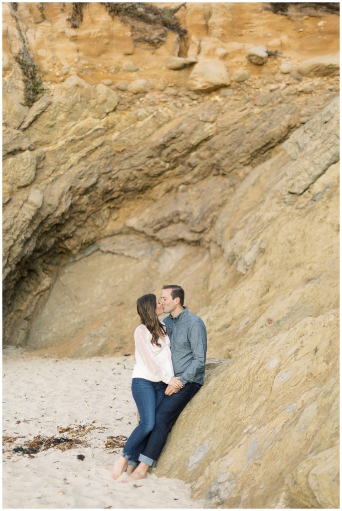 couple on the beach sharing a kiss against the cliffs