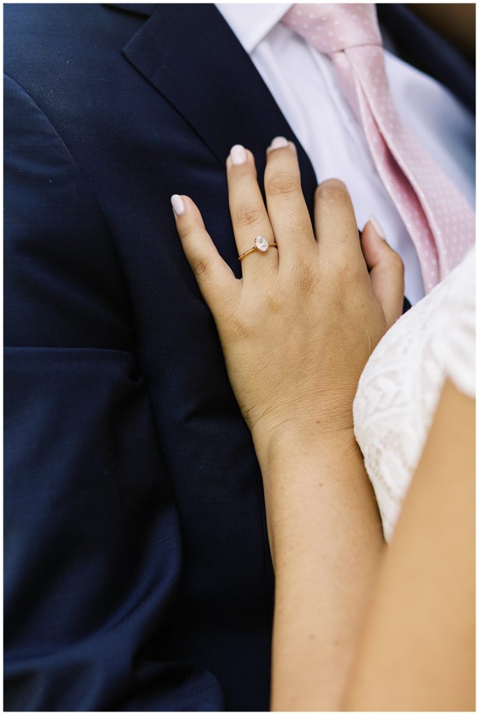 the bride's hand on her groom's tuxedo, focusing on her wedding ring
