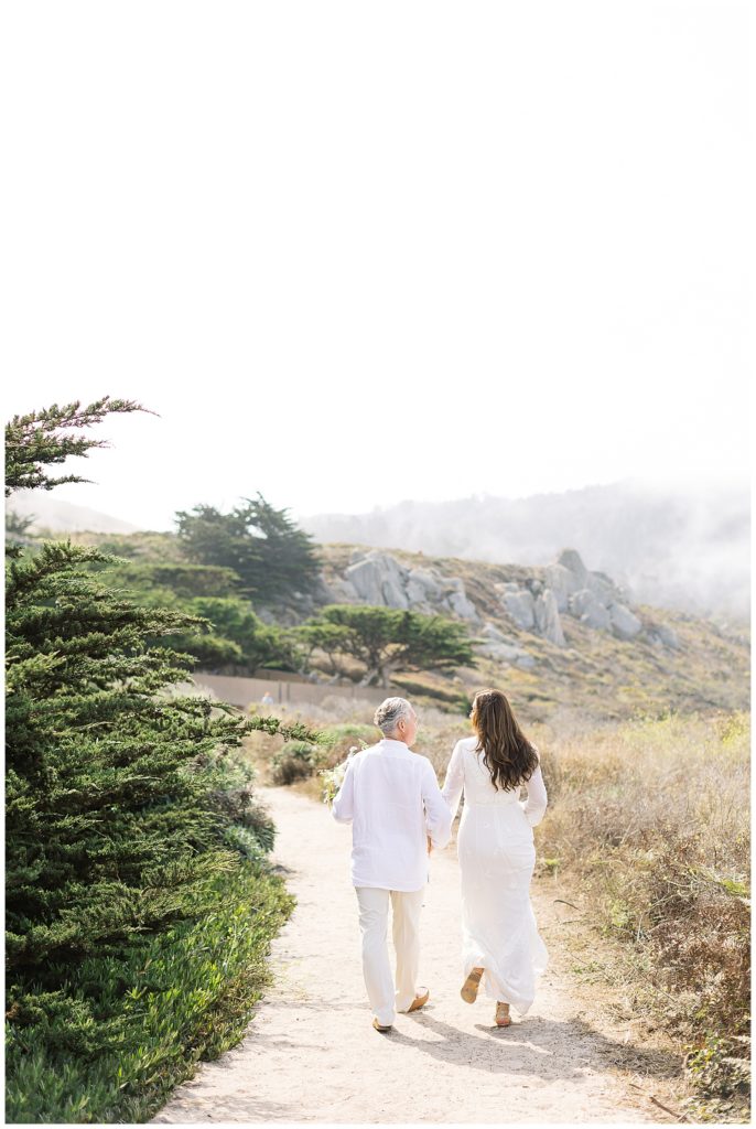 Carmel elopement portrait of the couple walking down a trail away from the camera
