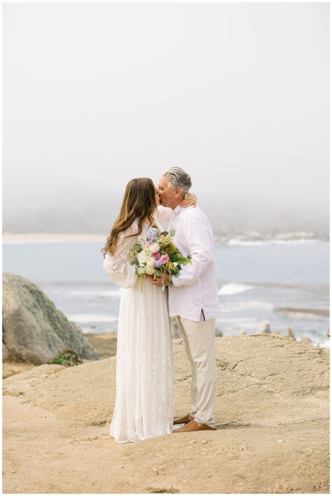 Carmel elopement portrait of the bride and groom sharing a kiss on the beach cliffs by film photographer AGS Photo Art