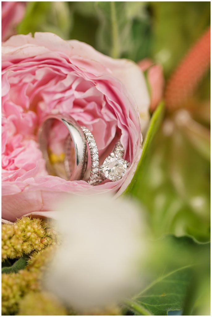 Carmel bride and groom's wedding rings nestled in pink flowers