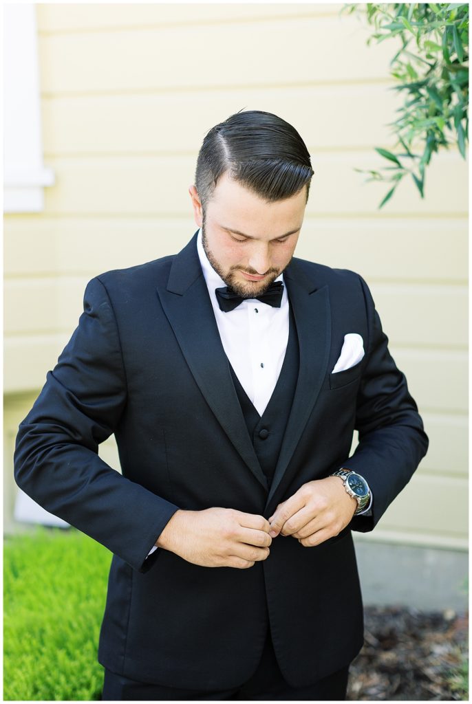 the groom buttoning his tuxedo at his Classic Monterey Bay Wedding
