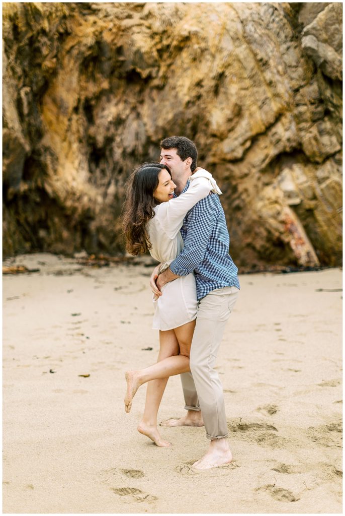 excited couple embracing and dancing on the sand
