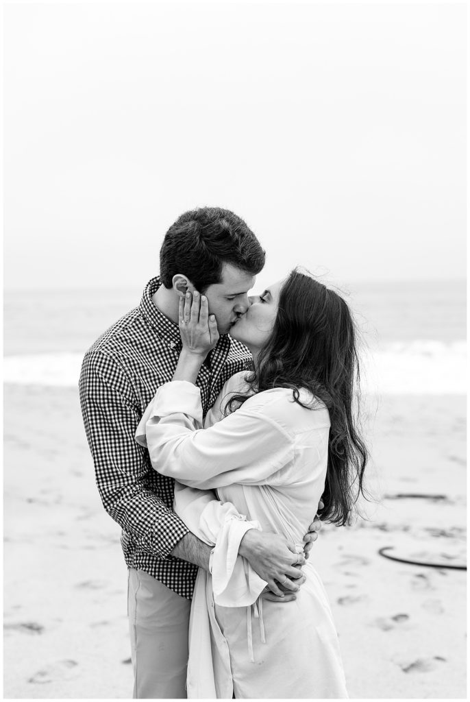 black and white portrait of the couple sharing a kiss on the beach