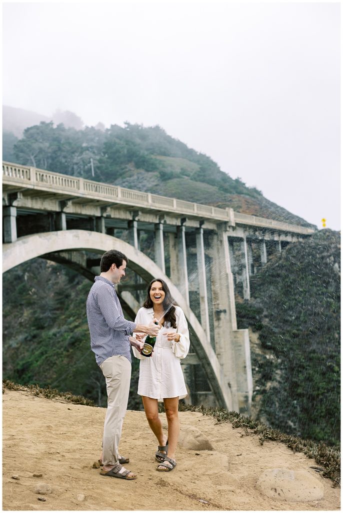 couple popping champagne at the Bixby Bridge