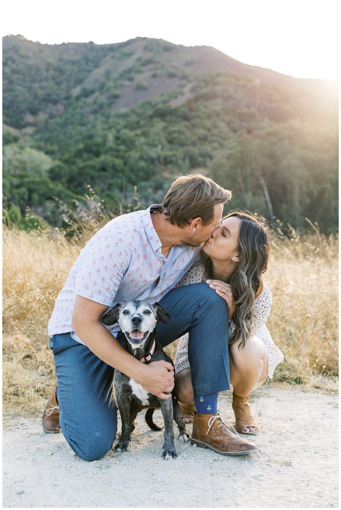 photo of couple sharing a kiss while holding their dog by film photographer AGS Photo Art