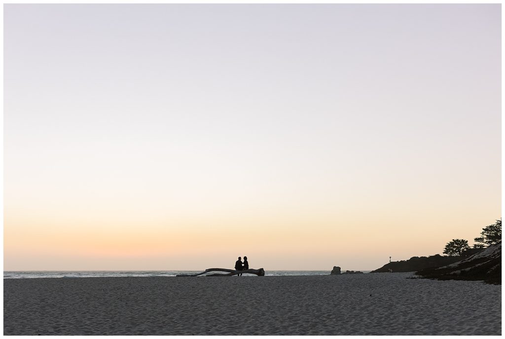 Carmel by the Sea sunset engagement session photo of the couple's shadows sitting on a log overlooking the beach by film photographer AGS Photo Art