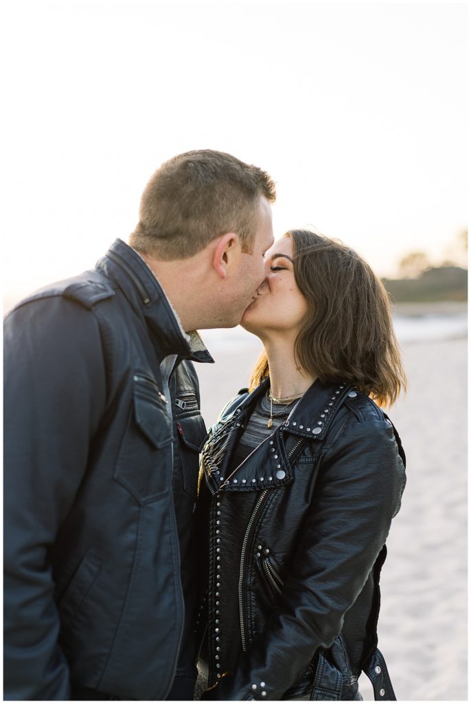 Carmel by the Sea engagement session portrait of couple dressed in black jackets sharing a kiss by film photographer AGS Photo Art