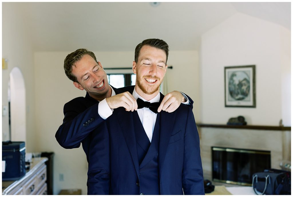 portrait of the groom and one of his groomsman adjusting his tie