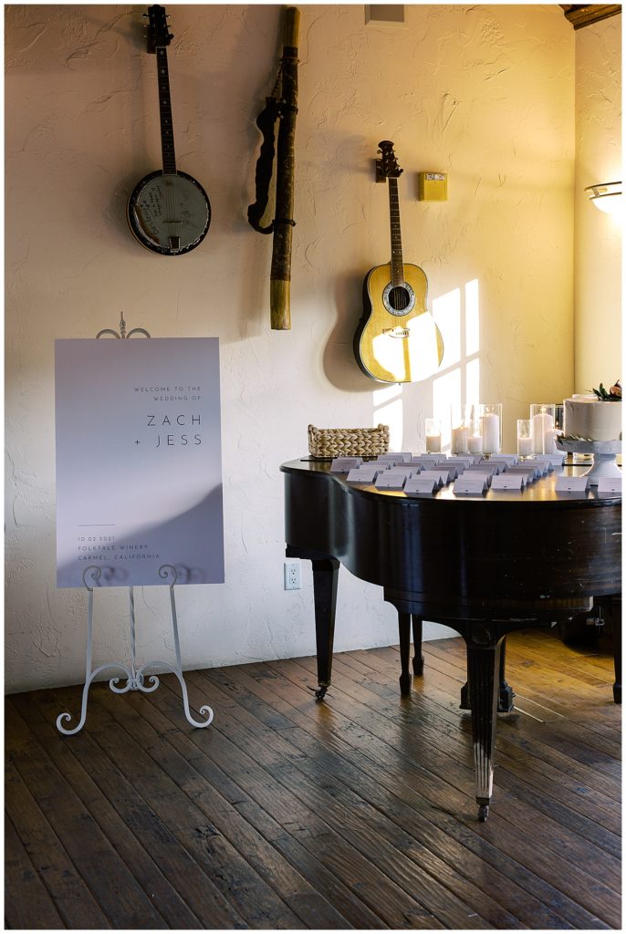 rustic stringed instruments hung on the walls and a grand piano with name cards and candles