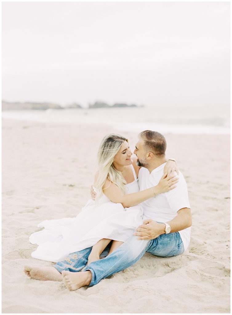 couple sitting together in the sand and smiling at each other
