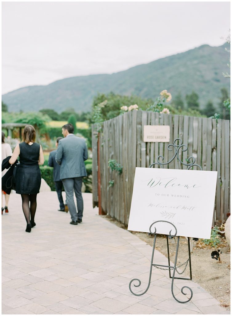 "welcome" sign leading to the wedding with guests coming in