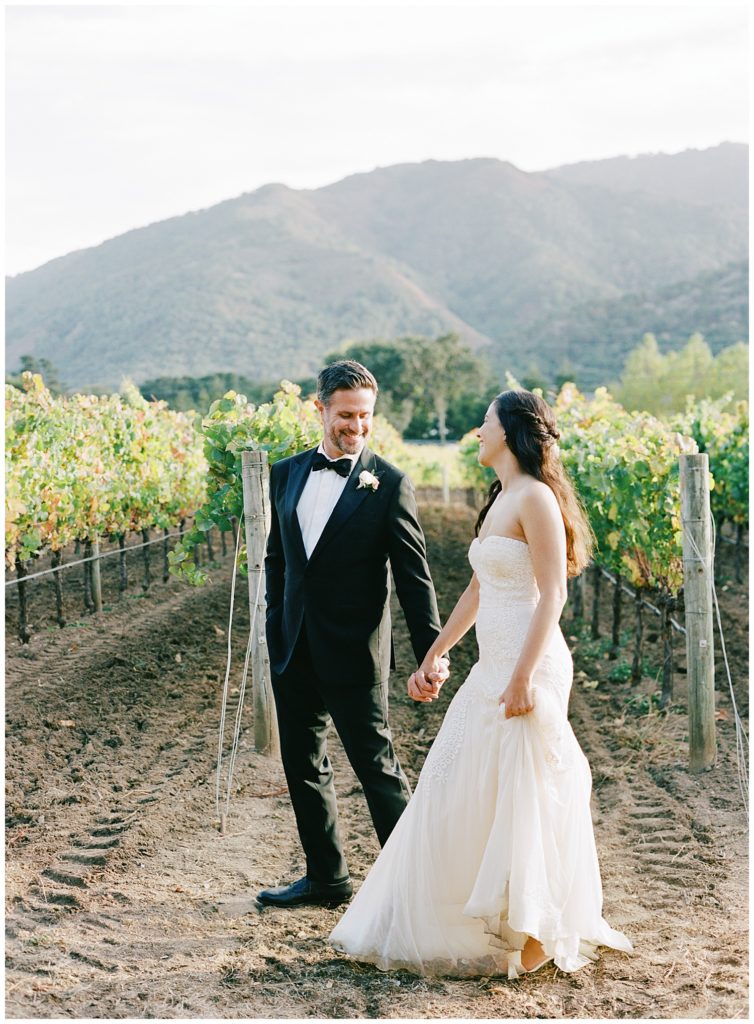bride and groom walking hand in hand through the vineyard at Bernardus Lodge & Spa