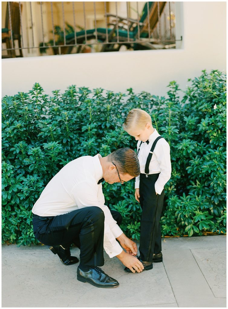 the groom tying his son's shoes for him at his MPCC Beach House intimate wedding