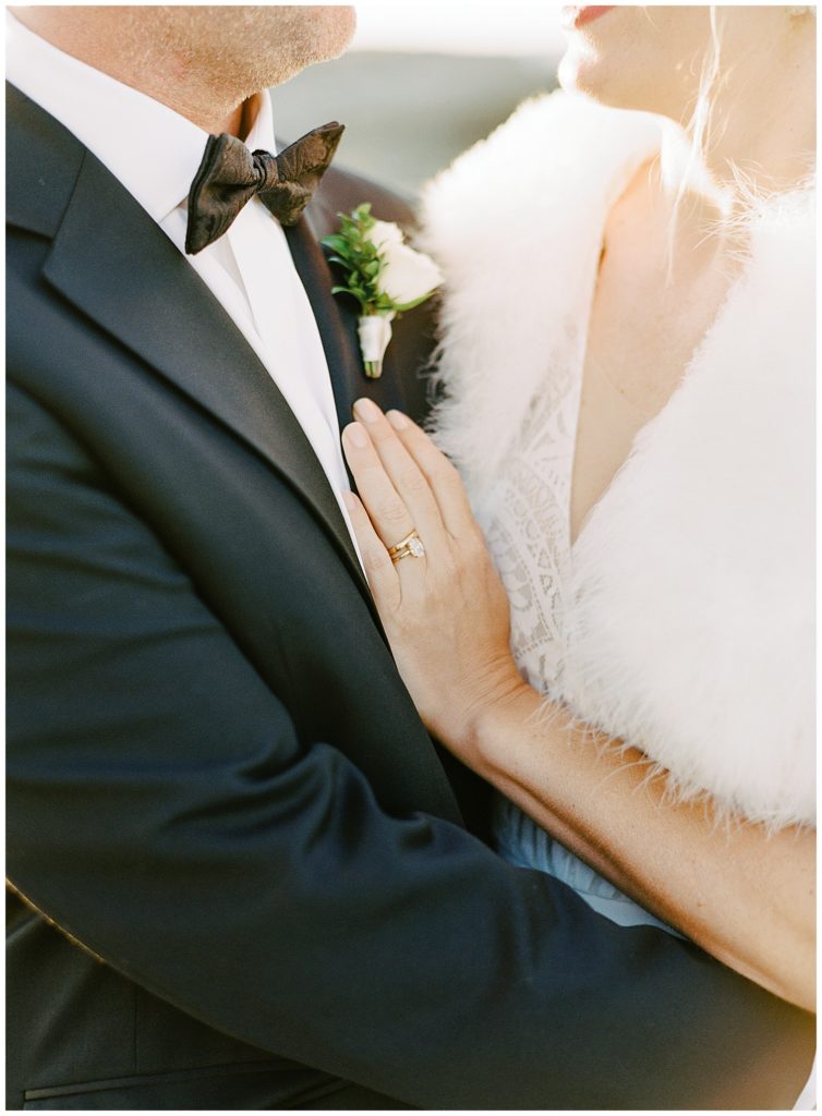 portrait of the bride wearing a fur coat embracing her groom by film photographer AGS Photo Art