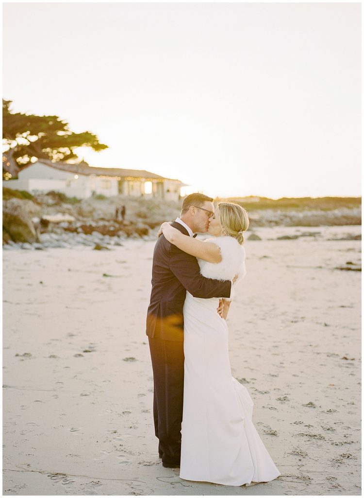 the married couple sharing a kiss on the beach at their MPCC Beach House intimate wedding