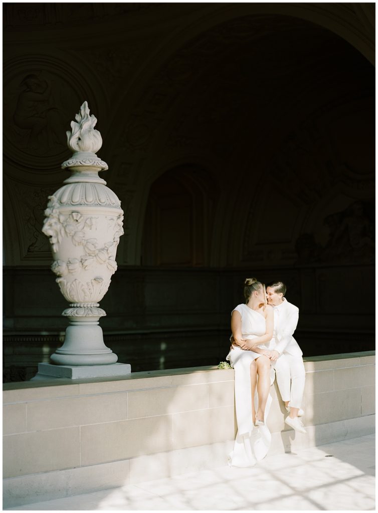 San Francisco City Hall Elopement portrait of two brides sitting in a patch of sun coming through the window