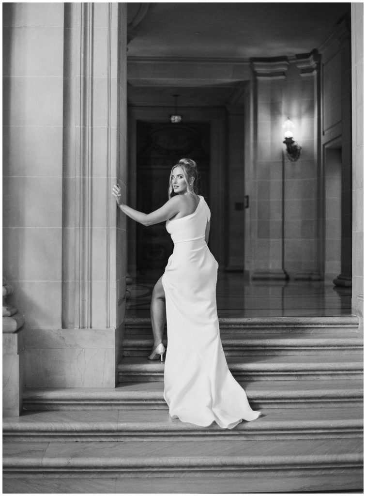 black and white portrait of the bride looking over her shoulder at the camera as she walks up the steps by film photographer AGS Photo Art