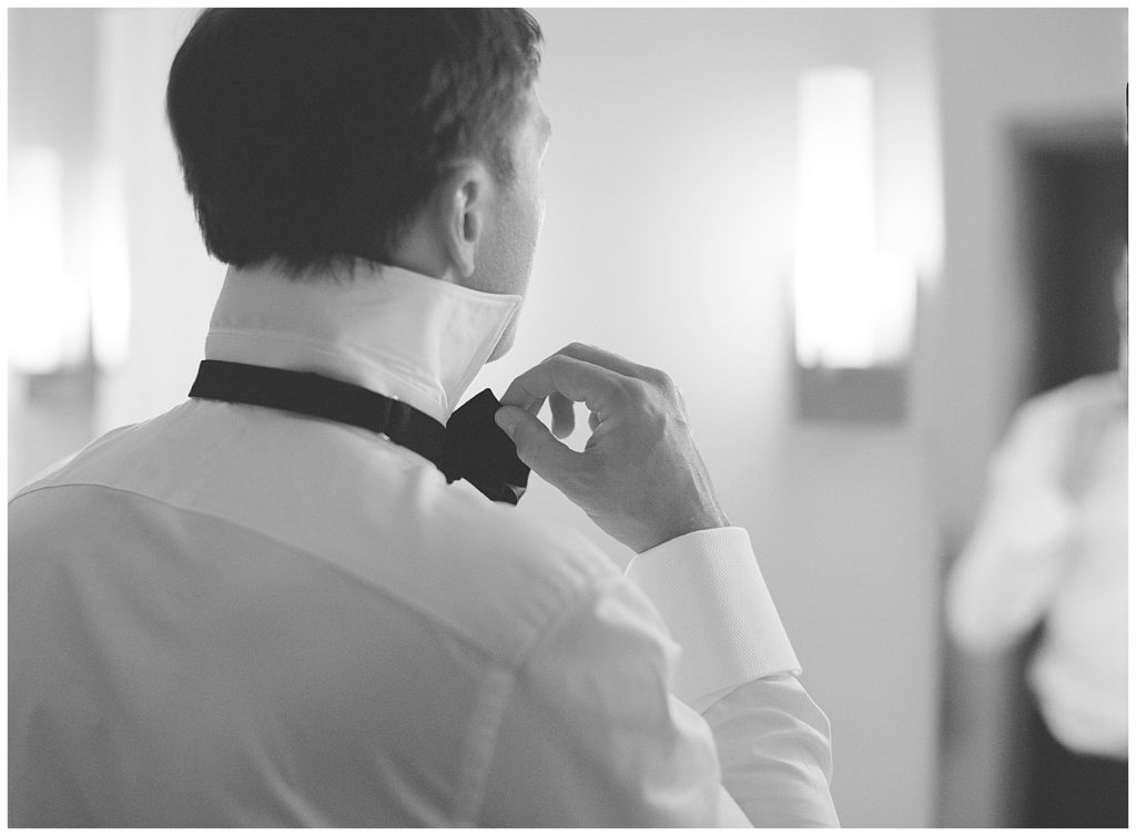 black and white getting ready photo of the groom adjusting his bowtie