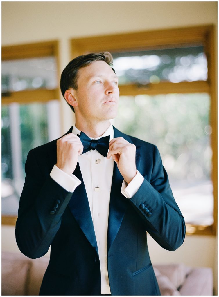 Wind & Sea Estate Big Sur wedding photo of the groom putting on his bowtie