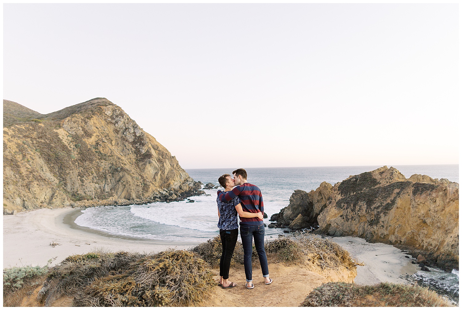 same sex couple sharing a kiss overlooking Pfeiffer Beach during their surprise engagement in Big Sur