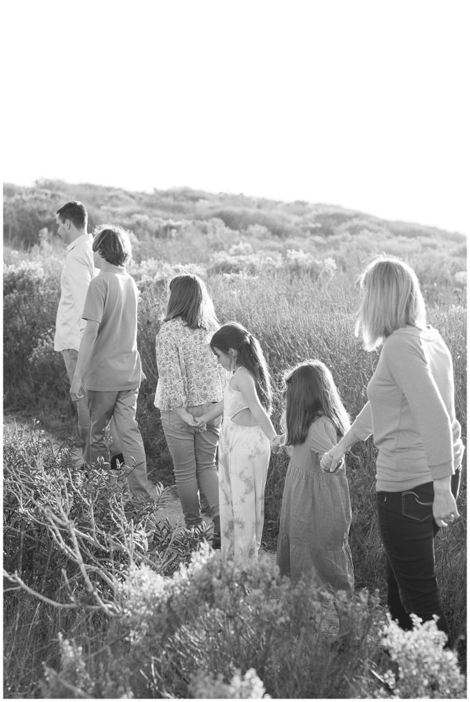 black and white Carmel family photoshoot with the family hand in hand walking up a hill
