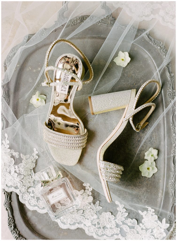 bride's Badgley Mischka heels on a silver platter with her veil, flowers, and perfume