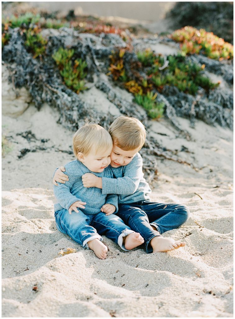 baby boys hugging and playing in the sand