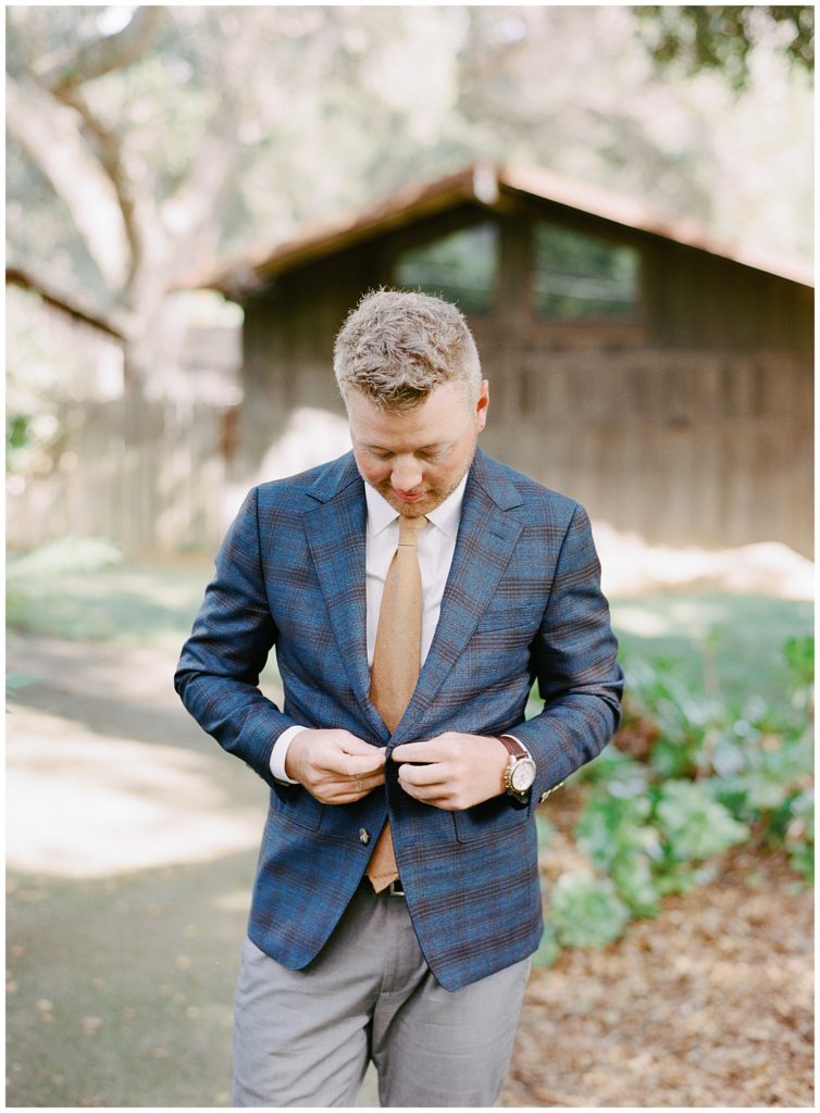 groom buttoning his suit jacket