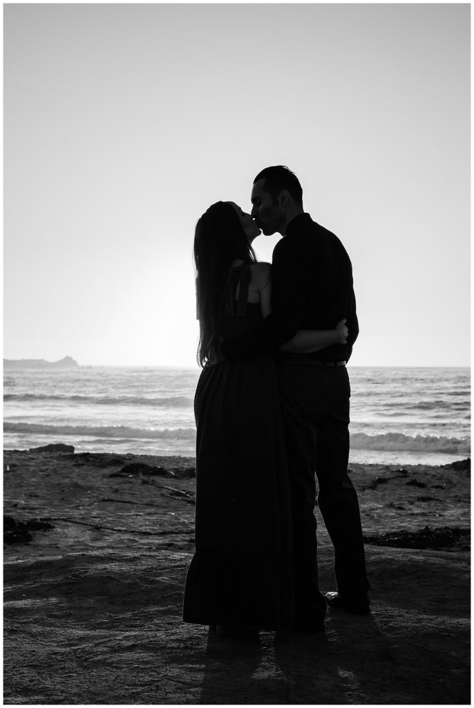 black and white Pebble Beach engagement portrait of the couple sharing a kiss