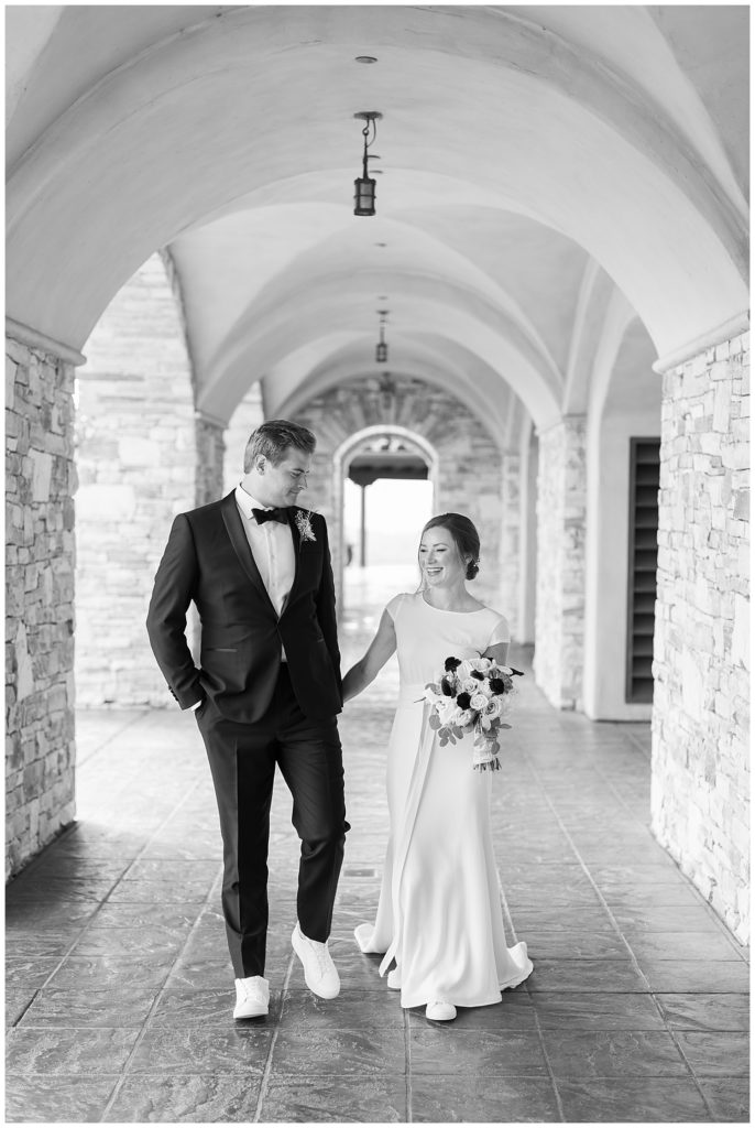 black and white portrait of the bride and groom walking together under the arches at Tehama