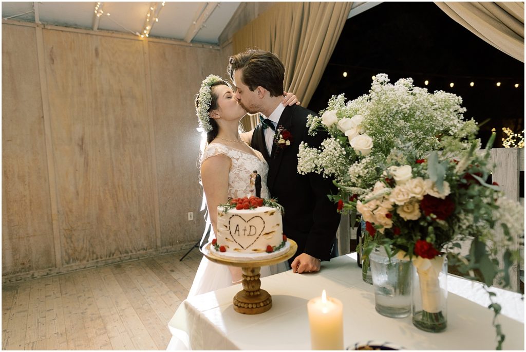 the bride and groom kissing during their reception by the wedding cake
