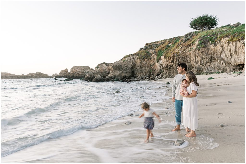 a family of four standing at the edge of the water looking out at the horizon in Big Sur for family shoot