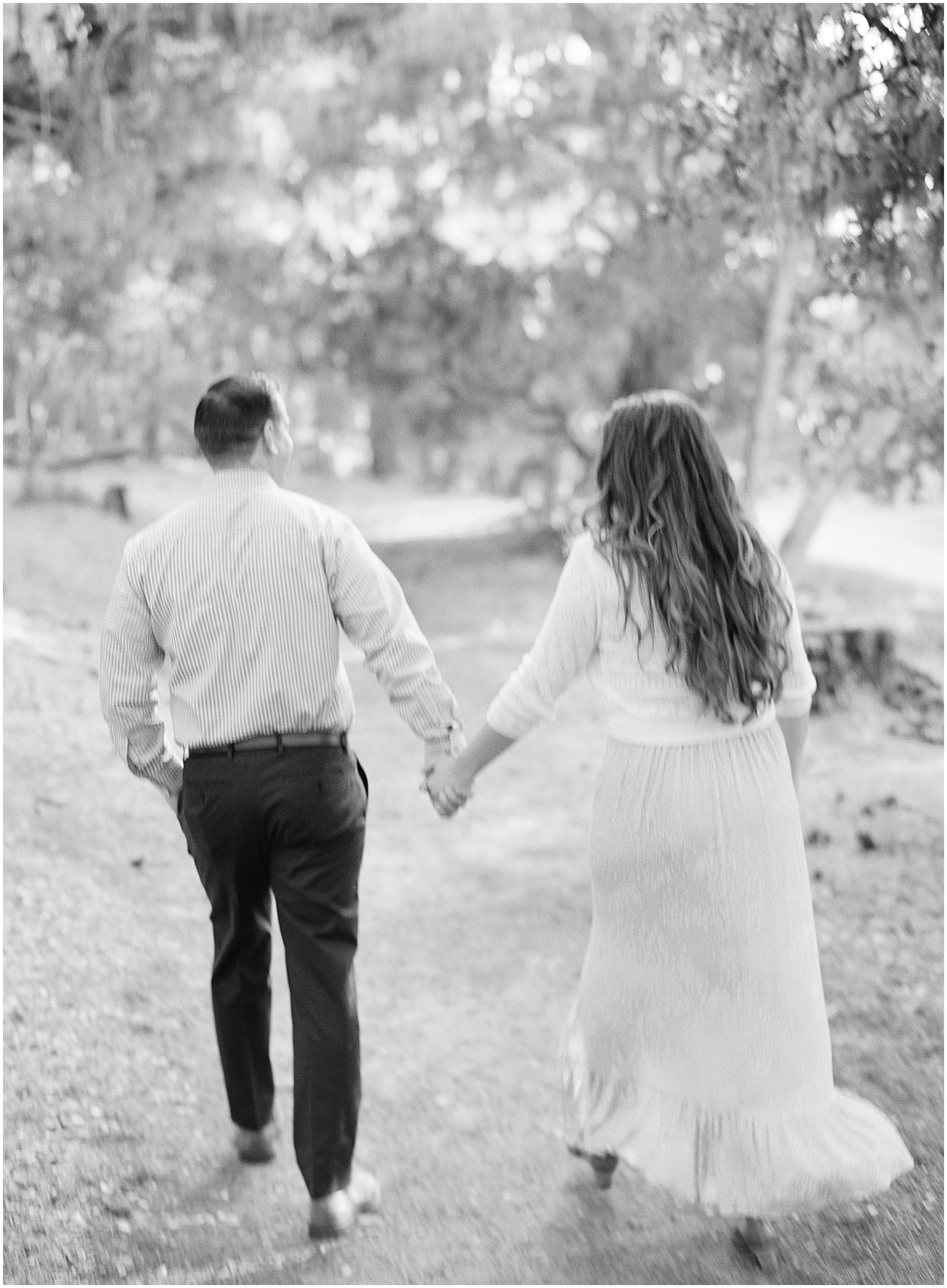 black and white portrait of couple holding hands and walking away