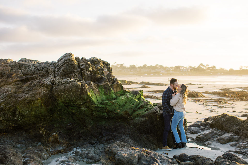 a landscape photo of a couple in an engagement pose on the beach during sunset